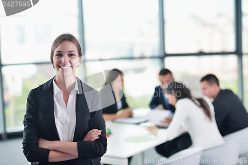 Image of business woman with her staff in background at office