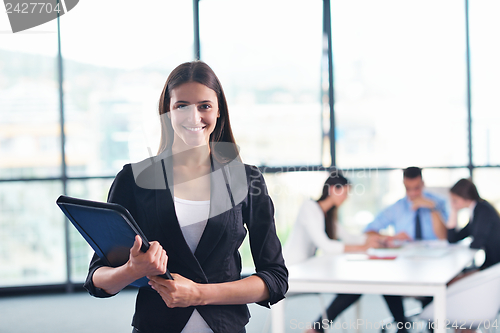 Image of business woman with her staff in background at office