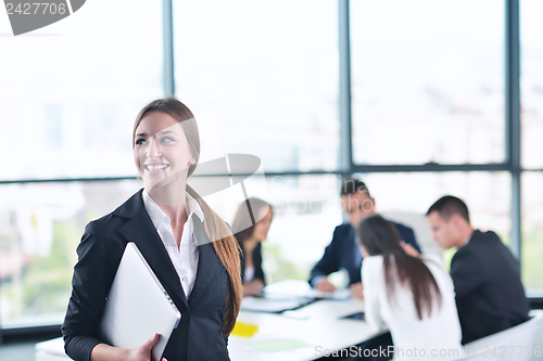 Image of business woman with her staff in background at office