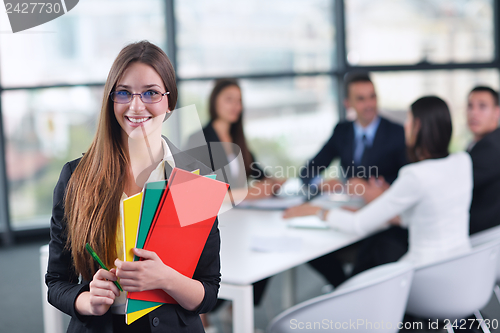 Image of business woman with her staff in background at office