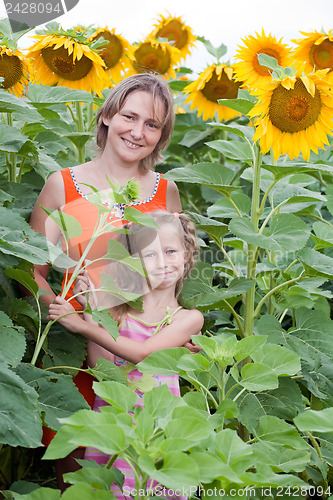 Image of mother and daughter standing at sunflowers field