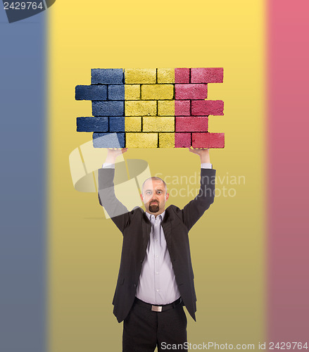 Image of Businessman holding a large piece of a brick wall