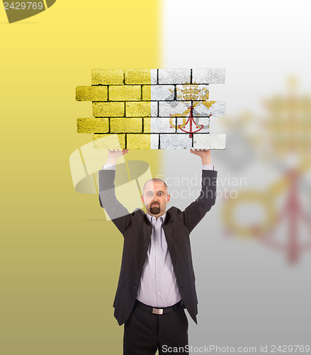 Image of Businessman holding a large piece of a brick wall