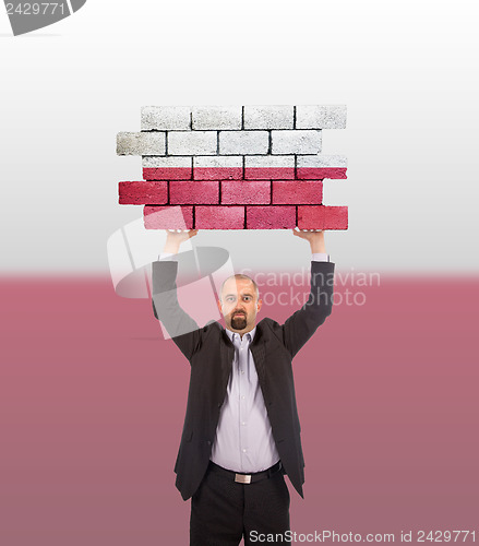 Image of Businessman holding a large piece of a brick wall