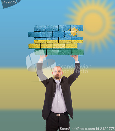 Image of Businessman holding a large piece of a brick wall