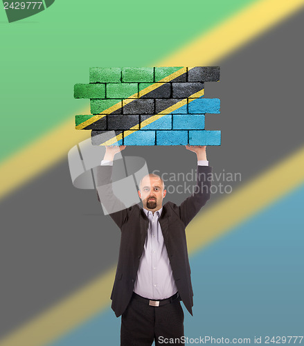 Image of Businessman holding a large piece of a brick wall