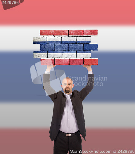 Image of Businessman holding a large piece of a brick wall