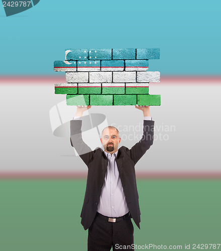 Image of Businessman holding a large piece of a brick wall
