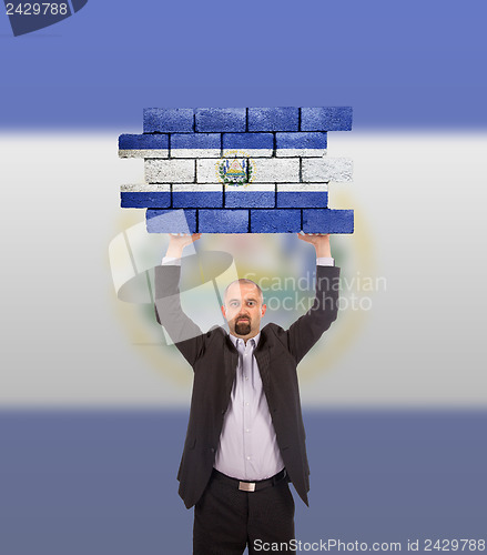 Image of Businessman holding a large piece of a brick wall