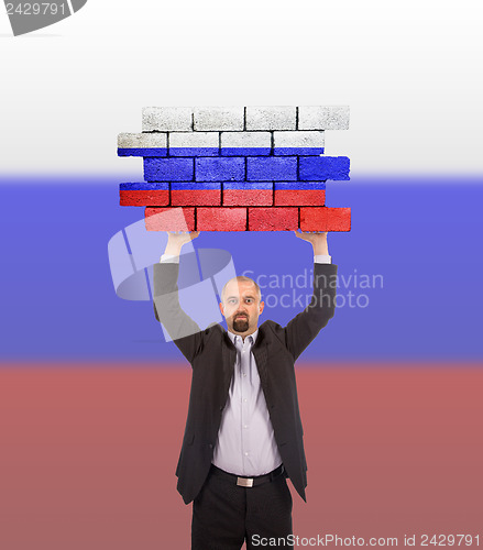 Image of Businessman holding a large piece of a brick wall