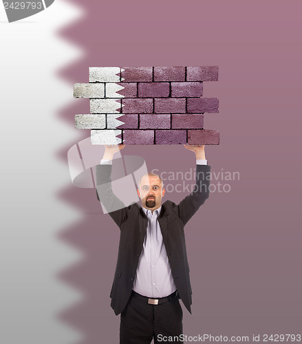 Image of Businessman holding a large piece of a brick wall