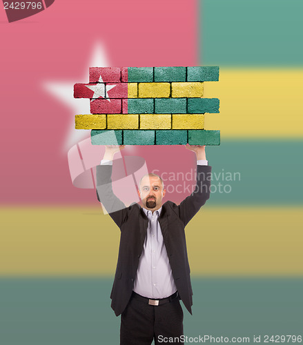 Image of Businessman holding a large piece of a brick wall