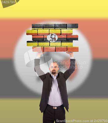 Image of Businessman holding a large piece of a brick wall