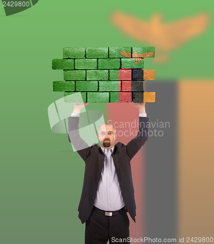 Image of Businessman holding a large piece of a brick wall