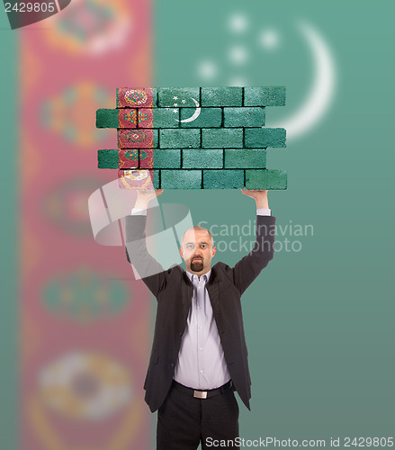 Image of Businessman holding a large piece of a brick wall