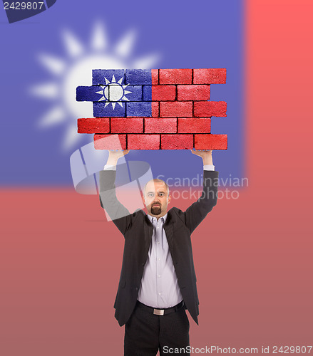 Image of Businessman holding a large piece of a brick wall