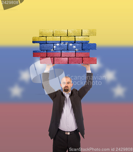 Image of Businessman holding a large piece of a brick wall