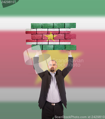 Image of Businessman holding a large piece of a brick wall