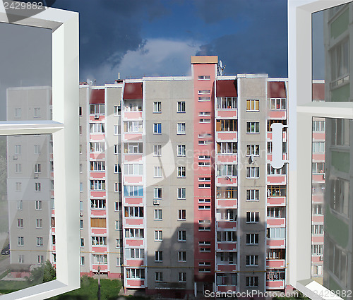 Image of opened window to multistorey house and raincloud