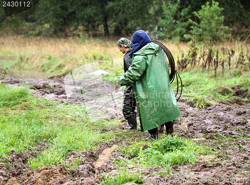 Image of Working going to rain on a muddy road