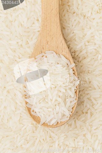 Image of Uncooked white rice on wooden teaspoon