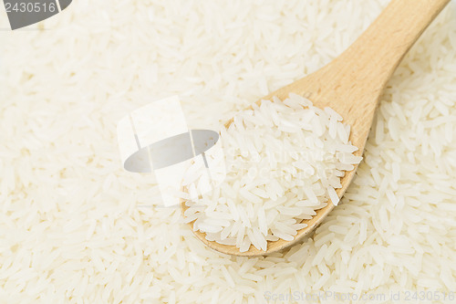 Image of Uncooked white rice on wooden teaspoon