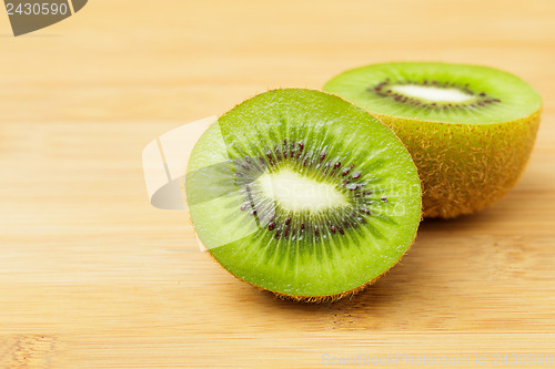 Image of Slices of green kiwi on wooden background