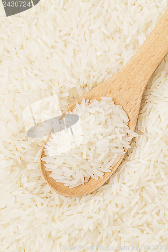 Image of Uncooked white rice on wooden spoon