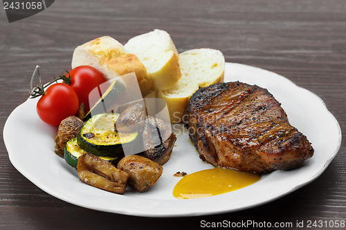 Image of pork steak with sauce, mustard and grilled vegetables