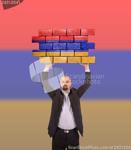 Image of Businessman holding a large piece of a brick wall