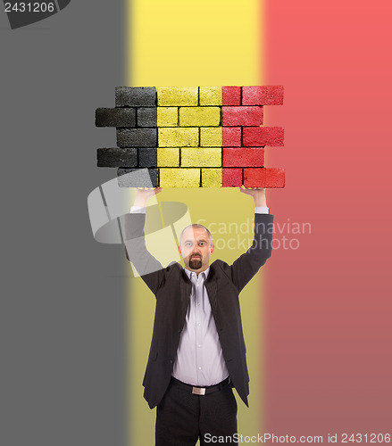 Image of Businessman holding a large piece of a brick wall