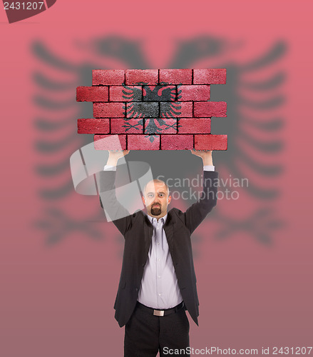 Image of Businessman holding a large piece of a brick wall