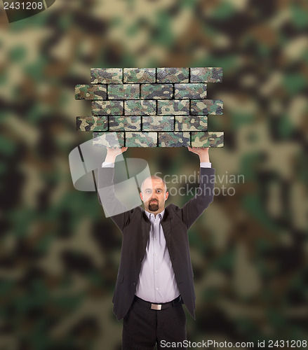 Image of Businessman holding a large piece of a brick wall