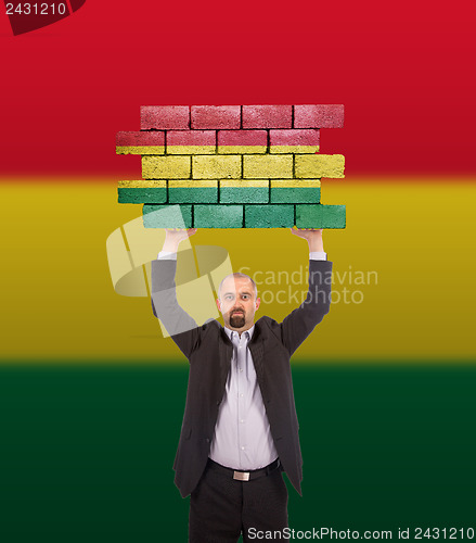 Image of Businessman holding a large piece of a brick wall