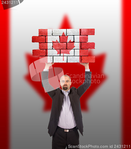 Image of Businessman holding a large piece of a brick wall