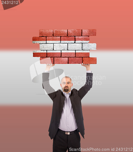 Image of Businessman holding a large piece of a brick wall