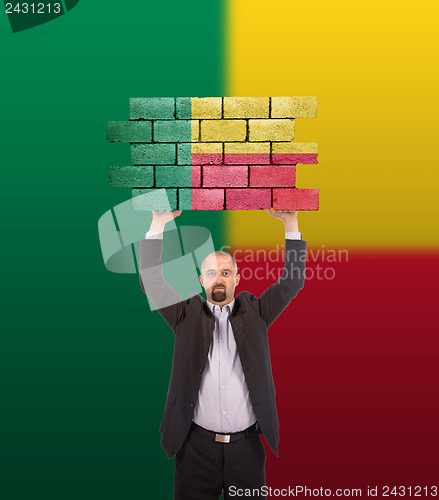 Image of Businessman holding a large piece of a brick wall