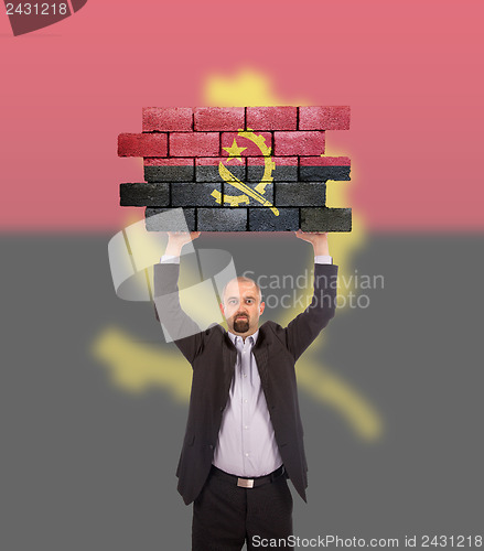 Image of Businessman holding a large piece of a brick wall