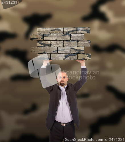 Image of Businessman holding a large piece of a brick wall