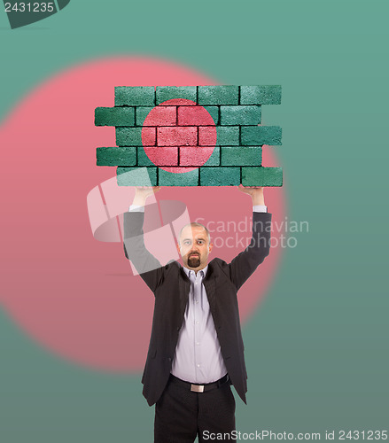 Image of Businessman holding a large piece of a brick wall