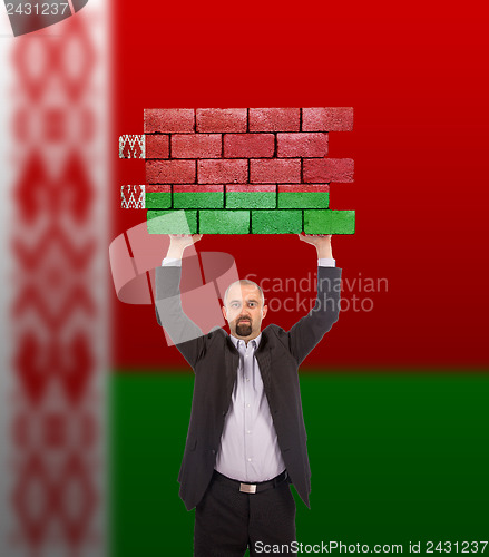 Image of Businessman holding a large piece of a brick wall