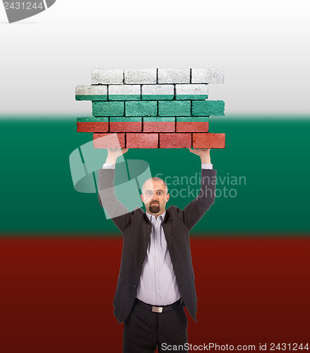 Image of Businessman holding a large piece of a brick wall