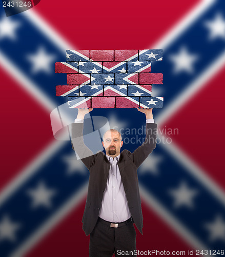 Image of Businessman holding a large piece of a brick wall