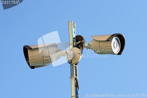 Image of Two security cameras against blue sky