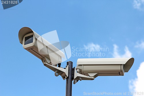 Image of Two security cameras against blue sky