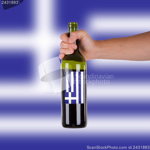 Image of Hand holding a bottle of red wine