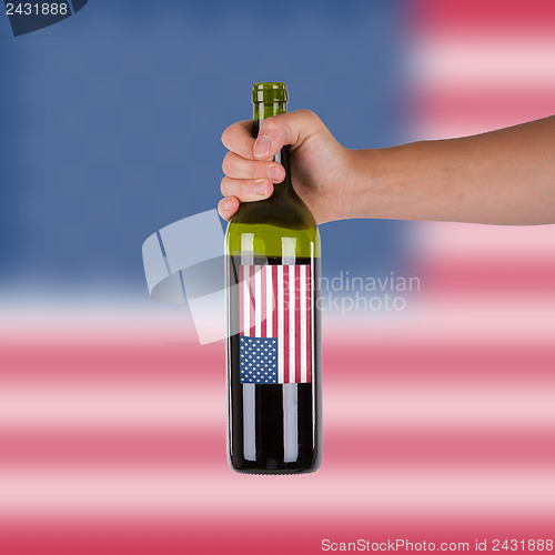 Image of Hand holding a bottle of red wine