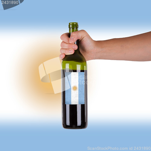 Image of Hand holding a bottle of red wine