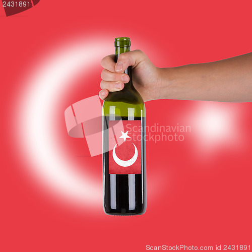 Image of Hand holding a bottle of red wine