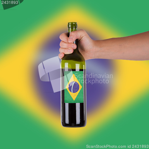 Image of Hand holding a bottle of red wine